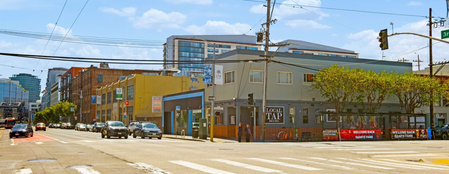a crosswalk with buildings and cars lined with trees