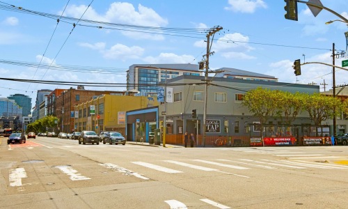 a crosswalk with buildings and cars lined with trees
