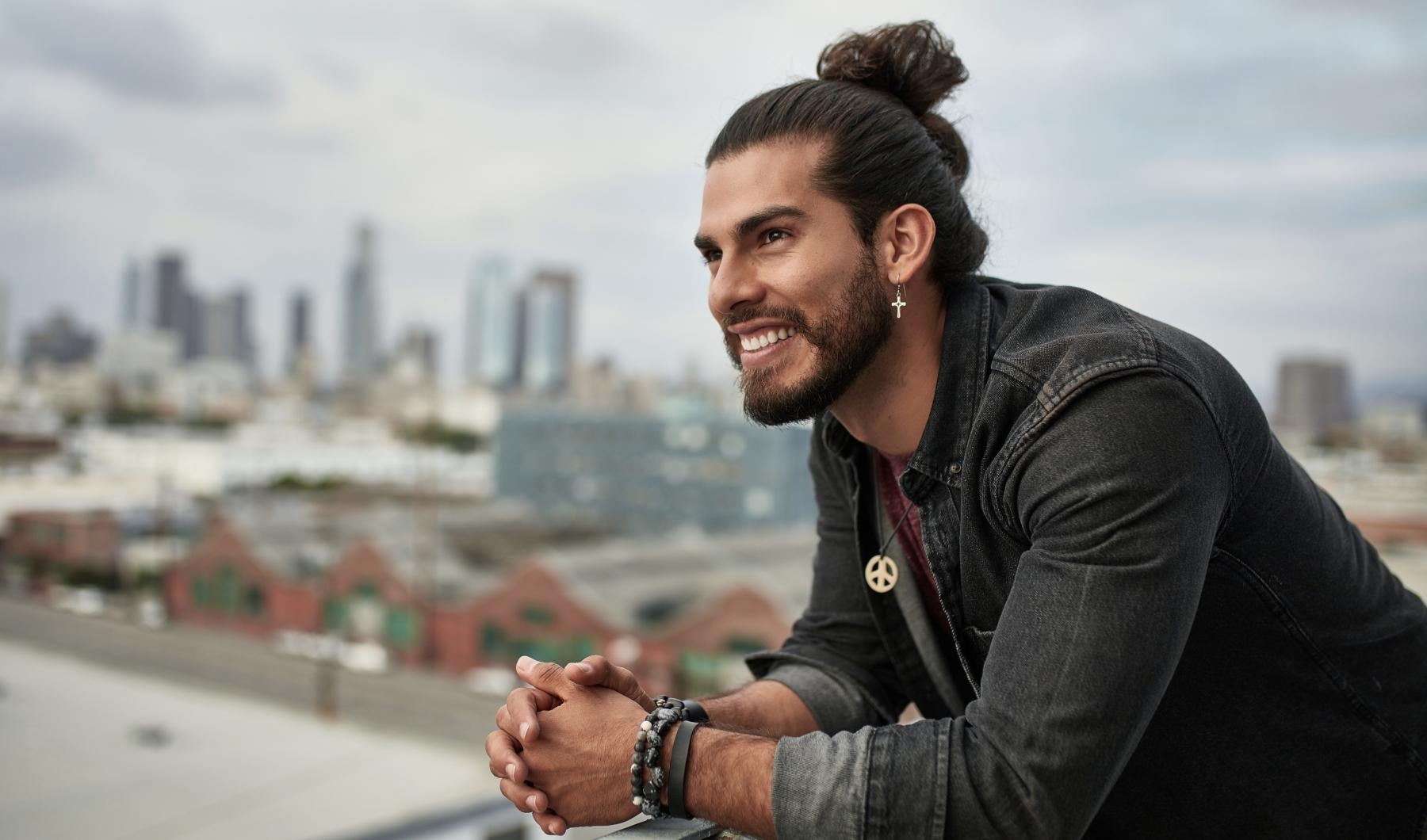 a man leaning on a railing with a city in the background