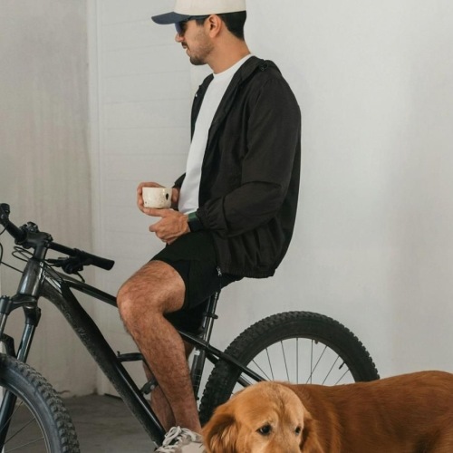 a man sitting on a bike next to a dog