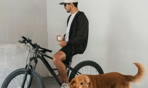 a man sitting on a bike next to a dog